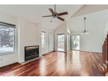 Bright living room with a fireplace, ceiling fan, vaulted ceiling and hardwood floors at 2121 S Troy Way, Aurora, CO 80014