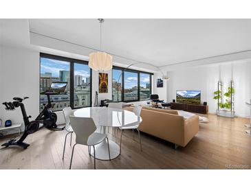 Open-concept living area with city views, modern furnishings, and hardwood flooring at 1750 Wewatta St # 700, Denver, CO 80202