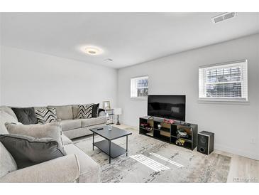 Bright living room with modern decor, featuring a comfortable couch, sleek coffee table, and entertainment center at 5183 Durham Ct, Denver, CO 80239