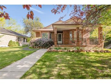Charming brick home featuring a covered front porch with lovely landscaping and healthy green lawn at 306 E Iowa Ave, Berthoud, CO 80513