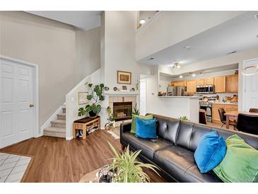 Cozy living room featuring a fireplace, comfortable seating, and an open view to the kitchen at 8371 S Upham Way # 208, Littleton, CO 80128
