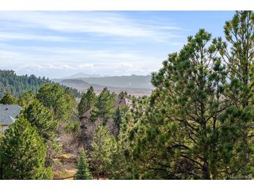 Scenic mountain view featuring evergreen trees and rolling hillsides under a partly cloudy sky at 7332 Woodglen Pl, Castle Pines, CO 80108