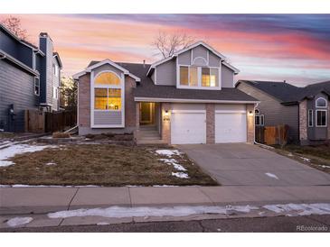 Two-story home with a gray exterior, two-car garage, and well-manicured lawn at 6765 Tabor St, Arvada, CO 80004