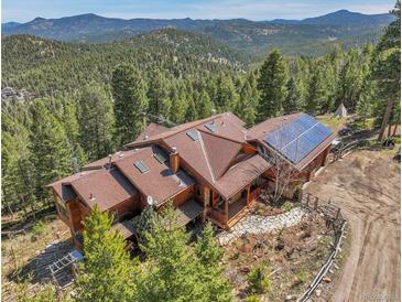 Stunning aerial view of mountain home with solar panels and beautiful surrounding forest at 33121 Lynx Ln, Evergreen, CO 80439