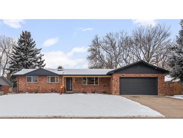 Ranch style home with brick facade, updated garage door, and snowy front yard at 6051 Welch St, Arvada, CO 80004