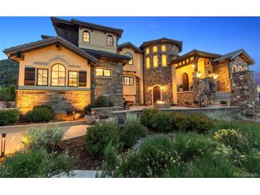 Stunning stone and stucco home with manicured landscaping and a charming front patio area at dusk at 7767 Dante Dr, Littleton, CO 80125