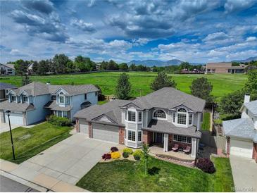 Inviting two-story home with a well-manicured lawn and colorful flowerbeds, set against a scenic backdrop at 1825 Keota Ln, Superior, CO 80027