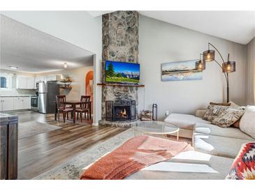 Inviting living room features a stone fireplace and views of kitchen and dining area at 1244 S Reed St # 2, Lakewood, CO 80232