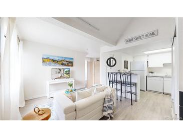 Bright living room featuring a modern sofa, decor, and a view into the updated kitchen at 8701 Huron St # 1-207, Thornton, CO 80260