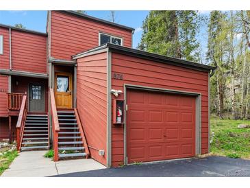 Red exterior showcasing a garage and stairway leading to the front door at 876 Broken Lance Dr, Breckenridge, CO 80424