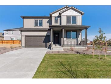 Charming two-story home featuring a covered porch, manicured lawn, and an attached two-car garage at 9882 Cathay St, Commerce City, CO 80022