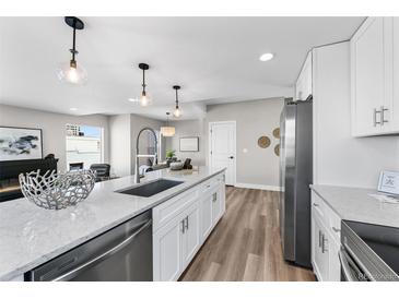 Bright, modern kitchen featuring an island with sink, white cabinets, and stainless steel appliances at 2140 S Ash St # 101, Denver, CO 80222