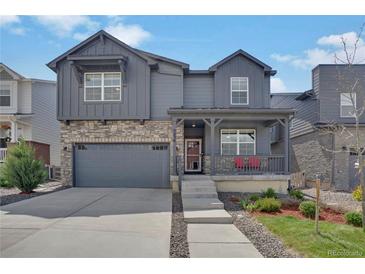 Charming two-story home with stone accents, a covered porch, a gray exterior, and a well-manicured lawn at 9836 Banner Peak St, Littleton, CO 80125