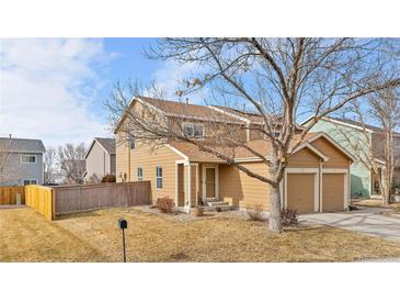 Charming two-story home featuring an attached two-car garage and a well-maintained front yard at 873 Mockingbird St, Brighton, CO 80601