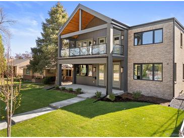 Modern two-story home featuring a covered balcony, gray siding, brick accents, and a well-manicured front lawn at 2610 N Monroe St, Denver, CO 80205