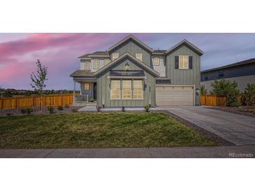 Beautiful two-story home with manicured lawn and modern architectural details at dusk at 6255 Kenzie Cir, Castle Pines, CO 80108