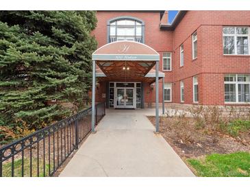 Inviting entrance with covered walkway, mature trees, and brick exterior at 300 Hudson at 300 Hudson St # 109, Denver, CO 80220