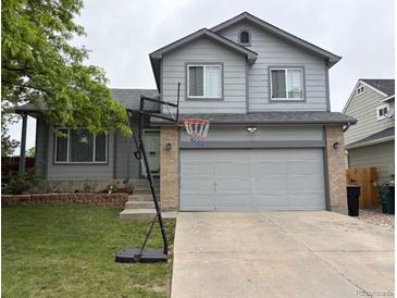 Charming gray two-story home with a basketball hoop and attached two car garage, and landscaped front yard at 12119 Forest St, Thornton, CO 80241