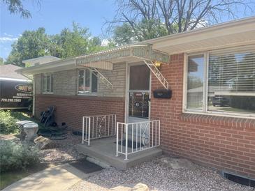 Charming brick home with a decorative metal awning over the front porch at 451 Lansing St, Aurora, CO 80010