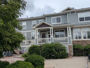 Two story home features a covered porch, green foliage and a partial stone facade at 9578 Pearl Cir # 105, Parker, CO 80134