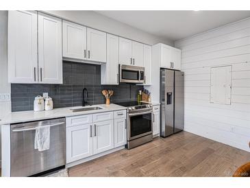 Modern kitchen featuring white cabinetry, stainless steel appliances, and sleek countertops at 2466 S Delaware St # 3, Denver, CO 80223
