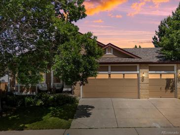 Charming home exterior featuring a three car garage and beautiful landscaping at sunset at 885 Sage Sparrow Cir, Highlands Ranch, CO 80129
