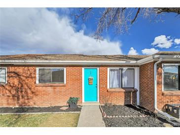 Charming brick home featuring a vibrant turquoise door with hanging basket, and manicured landscaping at 5211 W 4Th Ave # C, Lakewood, CO 80226