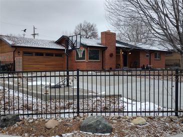 Charming brick home with a basketball hoop, updated wooden garage door and a manicured front yard with a fence at 2700 S High St, Denver, CO 80210