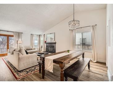 Open-concept living room and dining area with fireplace and hardwood floors and lots of natural light at 7586 Chase St, Arvada, CO 80003