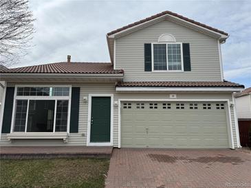 Charming two-story home featuring a red brick driveway, a green door, and a finished two-car garage at 20000 E Mitchell Pl # 35, Denver, CO 80249