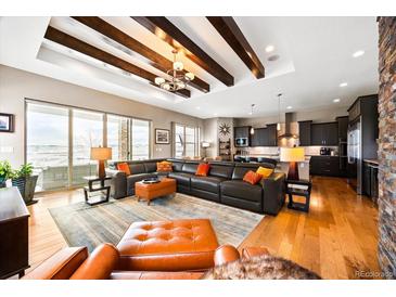 Spacious living room with hardwood floors, a leather sectional sofa, and a modern fireplace at 18722 W 87Th Ave, Arvada, CO 80007