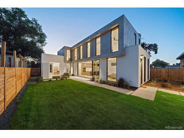 Modern home with a large lawn, a patio, and large windows showcasing the interior at 1626 S Sherman St, Denver, CO 80210