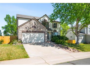 Charming two-story home featuring a stone facade, lush lawn, and an attached two-car garage at 19817 E Prentice Ave, Centennial, CO 80015