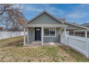 Charming single-story home featuring a covered front porch and classic architectural details with a white picket fence at 6660 Locust St, Commerce City, CO 80022