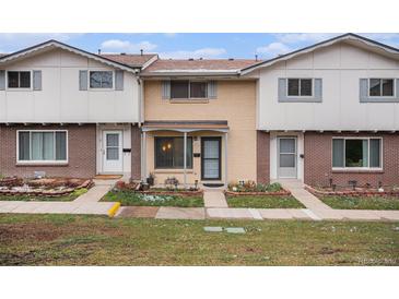 Charming townhome featuring a brick facade and covered front porch, complimented by an inviting landscaped yard at 12661 W Alameda Dr, Lakewood, CO 80228