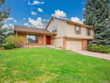 Two-story home boasts a red door, brick accents, tan siding, and well-maintained front lawn at 8546 E Mineral Cir, Centennial, CO 80112