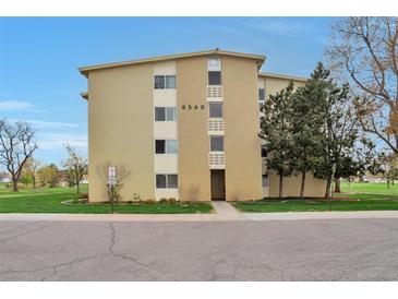 Tan-colored building exterior with well-manicured lawn and mature trees in a park-like setting at 9340 E Center Ave # 8A, Denver, CO 80247