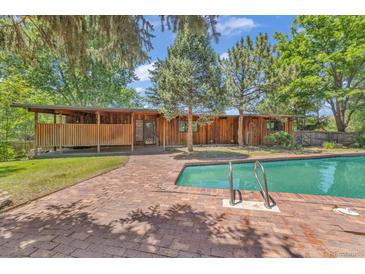 Wood house exterior featuring an outdoor pool surrounded by a brick deck and a wooden porch at 1 Lindenwood Dr, Littleton, CO 80120