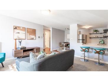 Inviting living room featuring a modern sofa, stylish decor, and open layout to the dining and kitchen area at 1260 York St # 204, Denver, CO 80206