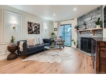 Bright living room with a stone fireplace, modern decor, and hardwood flooring at 8335 Fairmount Dr # 11-203, Denver, CO 80247