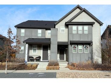 Two story home featuring a grey exterior, covered porch, and tidy front yard at 8157 E 53Rd Dr, Denver, CO 80238