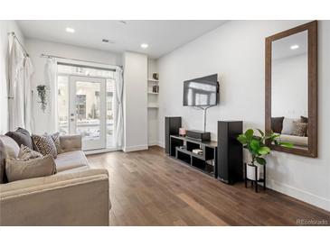 Bright living room featuring hardwood floors, a modern entertainment center, and neutral tones at 1898 S Bannock St # 103, Denver, CO 80223