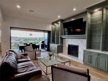 Inviting living room with a fireplace, built-ins, and a seamless indoor-outdoor flow to a scenic balcony at 16671 Red Cliff Cir, Morrison, CO 80465