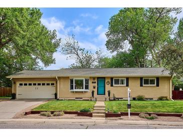 Charming single-story home with a well-maintained lawn, a blue door, and an attached garage at 6410 Independence Way, Arvada, CO 80004