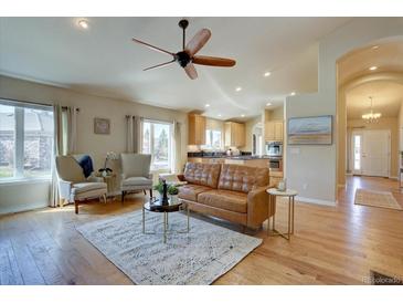 Inviting living room flows to kitchen, featuring hardwood floors and bright natural light at 13941 E Whitaker Dr, Aurora, CO 80015