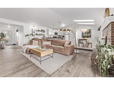 Open living room features a plush couch, light wood floors and a modern decor with plenty of natural light at 4408 E 107Th Pl, Thornton, CO 80233