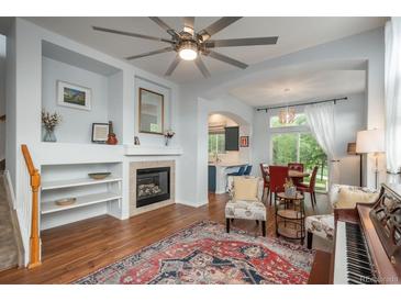 Inviting living room with fireplace, built-in shelving, and a large ceiling fan at 10696 Riverbrook Cir, Highlands Ranch, CO 80126