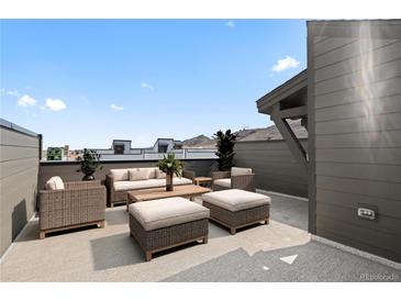 A luxurious rooftop patio featuring wicker furniture, including a sofa, chairs, ottomans, and a coffee table at 14412 Pansy Loop, Morrison, CO 80465