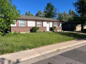 Ranch-style home featuring red shutters, brick accents, and a well-lit front yard with some uncut grass at 5543 Victor St, Denver, CO 80239