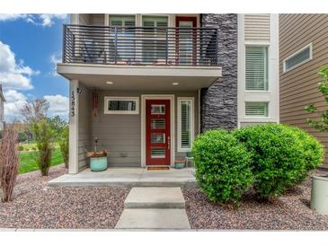 Charming home entrance features a red door, balcony, and neat landscaping at 15843 E Broncos Pl, Englewood, CO 80112